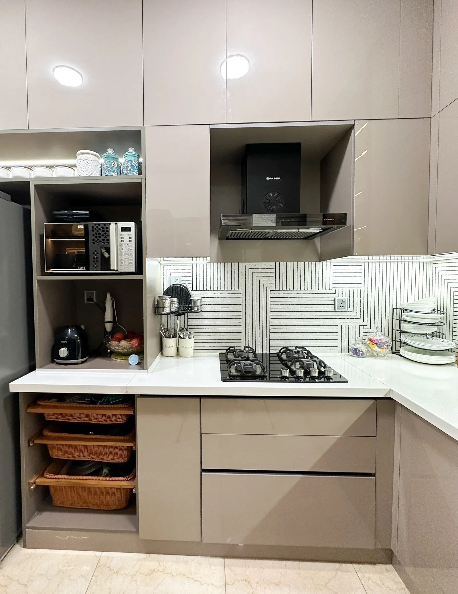 Kitchen with built-in chimney, taupe cabinets and pull-out baskets — Somani's Residence